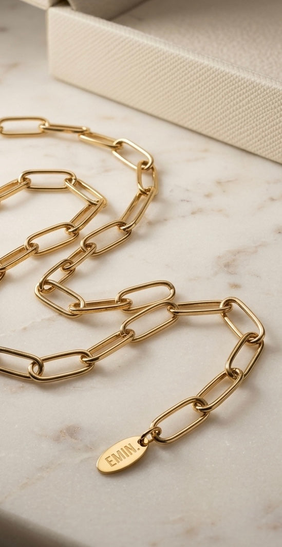Gold coin pendant paperclip chain necklace on marble surface
