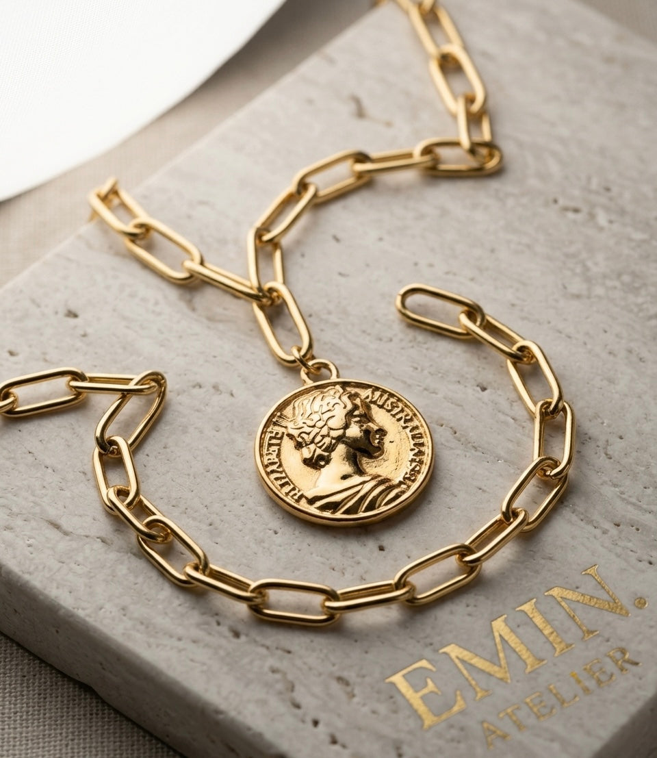 Gold coin pendant paperclip chain necklace on EMIN. branded stone surface